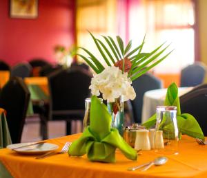 a table with a vase with white flowers on it at Bay Gardens Inn in Gros Islet
