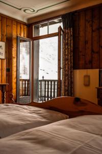 a bedroom with a bed and a large window at Hotel Fex in Sils Maria