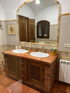 a bathroom with two sinks and a large mirror at Casa Rural Mijarra **** in Herrera del Duque