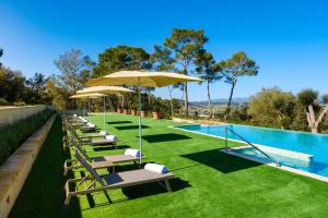 eine Reihe von Liegestühlen mit Sonnenschirmen neben einem Pool in der Unterkunft Finca Sa Bastida Luxury Retreat & Spa Adults Only in Sant Joan