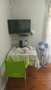 einen Tisch mit einem grünen Stuhl und einem TV in der Unterkunft Bertha's Place in Pretoria