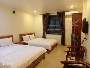 um quarto de hotel com duas camas e uma televisão em Guesthouse Anh Khang em Ha Long