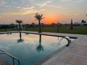 a swimming pool with a sunset in the background at Elegance Resort in Jait