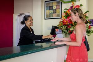 a woman in a red dress standing at a counter at Bay Gardens Inn in Gros Islet