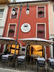 un ristorante con tavoli e ombrelloni di fronte a un edificio di Ca’ Bruno Masaneta a Grado