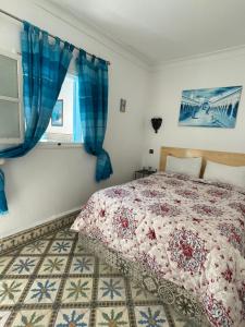 1 dormitorio con 1 cama con cortinas azules y ventana en Riad chez brahim, en Essaouira