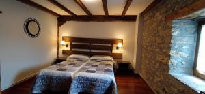 two beds in a room with a stone wall at Casa Rural Haitzetxea in Zugarramurdi