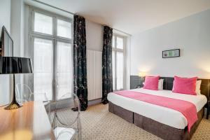 a bedroom with a large bed with pink pillows at Hotel Caumartin Opéra - Astotel in Paris