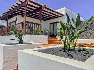 une maison avec deux plantes en pot devant elle dans l'établissement Villa 61 PlayaBlanca Lanzarote Pool Spa, à Playa Blanca