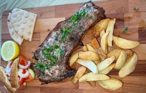 a wooden cutting board with a piece of meat and french fries at Elyssia Hotel in Pedoulas