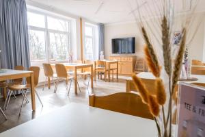 a dining room with tables and chairs and a tv at Jugendherberge Kappeln in Kappeln