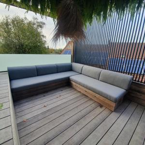 un sofá azul sentado en una terraza de madera en SUBSTANTIEL - Luxury Rooms & Wellness Suite en Brunehaut