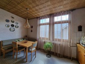 a dining room with a table and chairs and windows at Winzervilla in Ediger-Eller