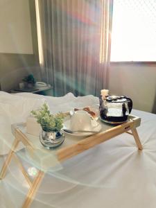 a tray with a tea set on a bed at Praia da Costa, SUNRISE STAY in Vila Velha