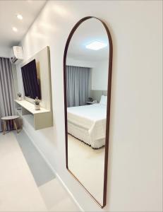 a mirror in a white room with a bed at Praia da Costa, SUNRISE STAY in Vila Velha
