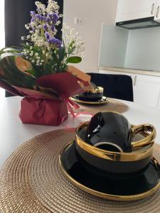 a table with a black and gold plate and a vase of flowers at Apartament Timisoara 4 in Timişoara