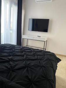 - une chambre avec un lit noir et une télévision à écran plat dans l'établissement Apartament Timisoara 4, à Timişoara
