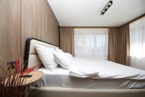 une chambre avec un lit avec des draps blancs et des oreillers dans l'établissement Nest Apartments Sarajevo, à Sarajevo