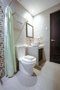 La salle de bains est pourvue de toilettes blanches et d'un lavabo. dans l'établissement Emerald Boutique Hotel, à Legazpi
