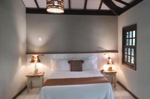 1 dormitorio con 1 cama grande y 2 lámparas en las mesas en Aldeia do Mar Hotel, en Itacaré