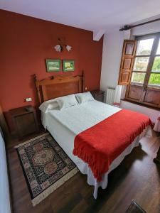 um quarto com uma cama grande e um cobertor vermelho em Posada Revolgo em Santillana del Mar