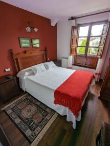a bedroom with a large bed with a red blanket at Posada Revolgo in Santillana del Mar
