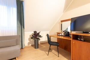 a room with a desk with a television and a chair at Hotel Restaurant Am Park in Waltrop