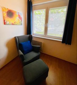 a room with a chair and a blue pillow and two windows at Ferienwohnung Rosenauer in Purbach am Neusiedlersee