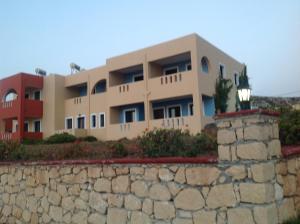 a building behind a stone wall with a street light at Archipelagos Apartments in Arkasa