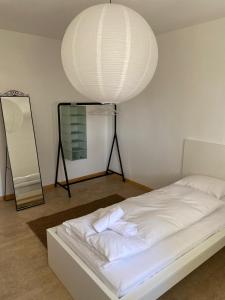 Schlafzimmer mit einem weißen Bett und einem Spiegel in der Unterkunft Bethaniaweg in Rüschlikon