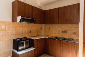 a kitchen with wooden cabinets and a sink and a microwave at Studio Sevasti in Kala Nera
