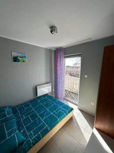 a bedroom with a blue bed and a window at Hacjenda in Łuszczewo