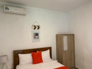 Umah Putih في نوسا بينيدا: غرفة نوم مع سرير مع وسائد برتقالية وبيضاء