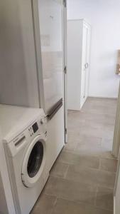 uma máquina de lavar e secar roupa num quarto com piso em azulejo em Nuevo apartamento en la playa de Castelldefels! em Castelldefels
