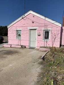 ein rosa Gebäude mit einer weißen Tür und Fenstern in der Unterkunft Pink Flamingo at the Beach cottage in North Camellia Acres