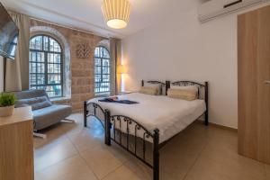 a bedroom with a bed and a couch and windows at Stay Jaffa Jerusalem in Jerusalem