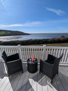 two chairs and a table on a deck with the ocean at LOCATION LOCATION Beautiful Modern Frontline Caravan Haven Littlesea Weymouth in Weymouth