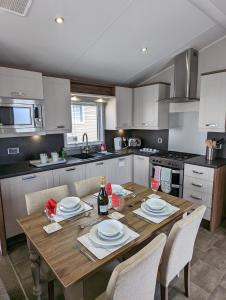a kitchen with a wooden table with white plates on it at LOCATION LOCATION Beautiful Modern Frontline Caravan Haven Littlesea Weymouth in Weymouth