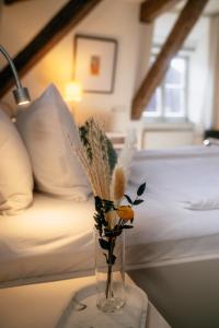 a vase with flowers on a table next to a bed at Weinbar & Gästehaus Himmelstoss in Dettelbach