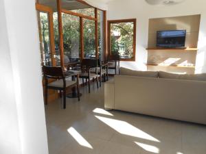 a living room with a couch and a table and chairs at La Posada Hotel in Pinamar
