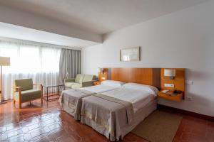 a hotel room with a large bed and a chair at Parador de Nerja in Nerja