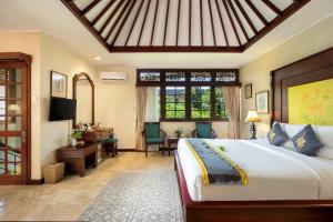 Dormitorio con cama, escritorio y TV en Royal Tunjung Hotel & Villa Legian - CHSE Certified, en Legian