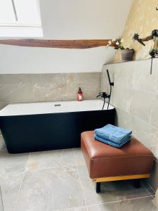 a bath tub in a bathroom with a stool and a bench at Domaine de La Vove in Corbon