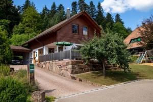 een houten huis met een hek en een boom bij Schwarzwald Chalets in Freudenstadt