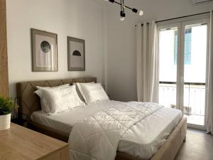 um quarto com uma cama com lençóis brancos e uma janela em Old courthouse apartment em Corfu Town