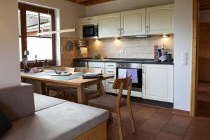 cocina con armarios blancos, mesa y sillas en Schwarzwald Chalets, en Freudenstadt