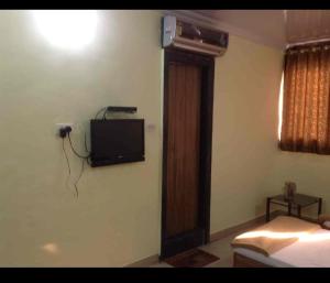 1 dormitorio con TV en la pared y 1 cama en Hotel Rachana Residency en Pune