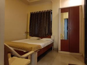 a small bedroom with a bed and a window at Hotel Rachana Residency in Pune
