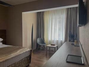 1 dormitorio con 1 cama, 1 silla y 1 ventana en Hotel Gloria Deluxe en Borovoye