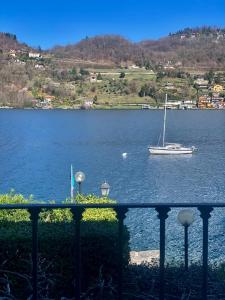 ein Segelboot im Wasser mit einem Boot in der Unterkunft Villa Giardino con pontile sul Lago D’Orta in riva in Orta San Giulio